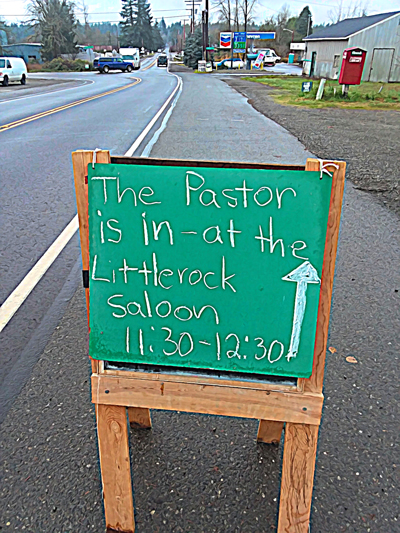 A sign reading, "The Pastor is in at the Littlerock Saloon 11:30 to 12:30" with an arrow pointing to saloon.